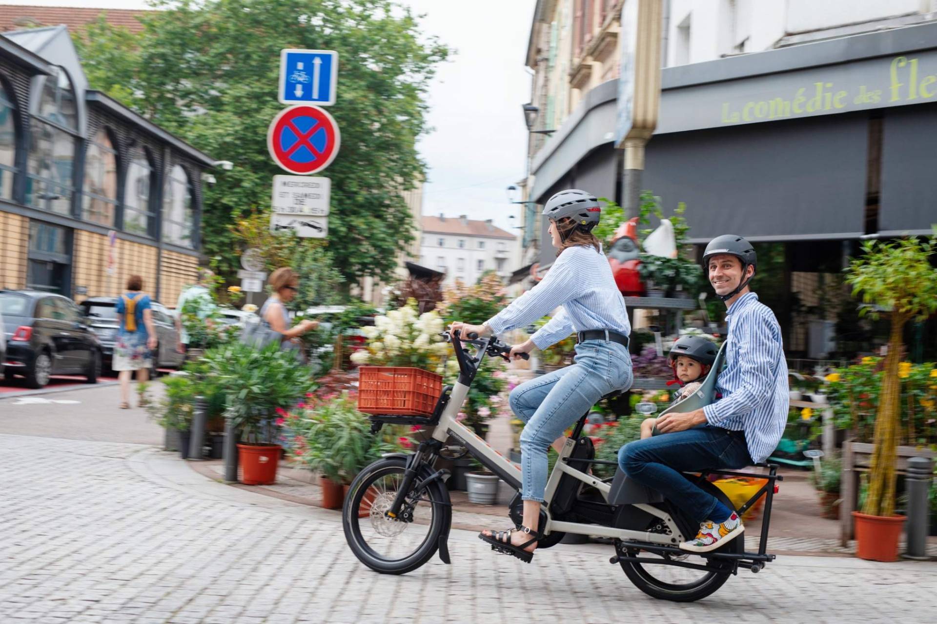 Famille à vélo cargo en ville avec un enfant sur le porte-bagages